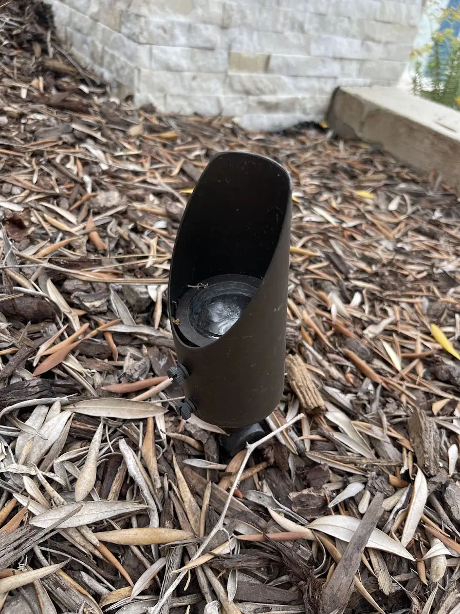 Bronze landscape uplight in a mulched planter bed