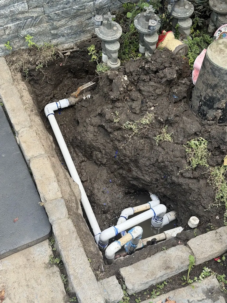 New white PVC pipe run to a row of sprinkler valves after a pipe break