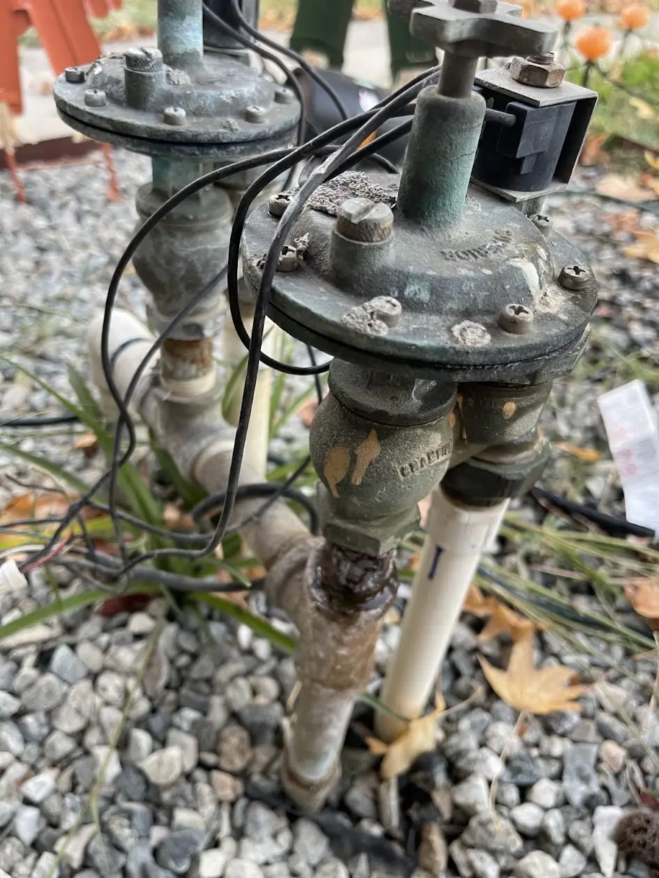 Old brass sprinkler valves on a rusted galvanized steel manifold