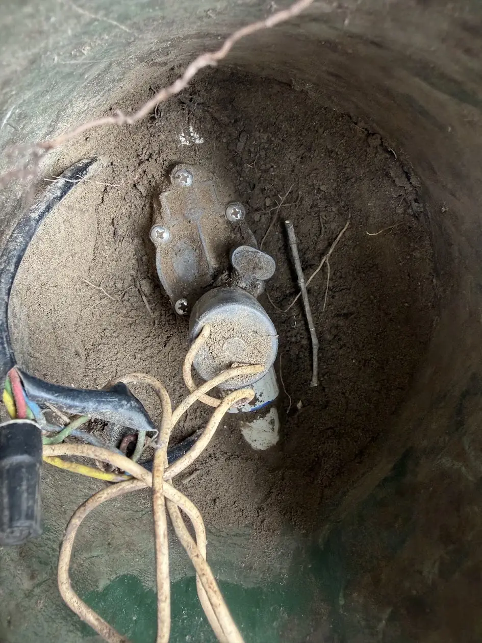 Sprinkler valve and control wires buried in dirt inside a valve box